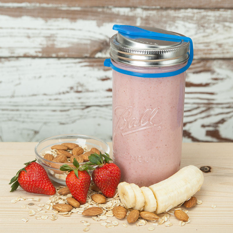 Blue poptop lid with plug closed on a 24 ounce mason jar filled with pink smoothie