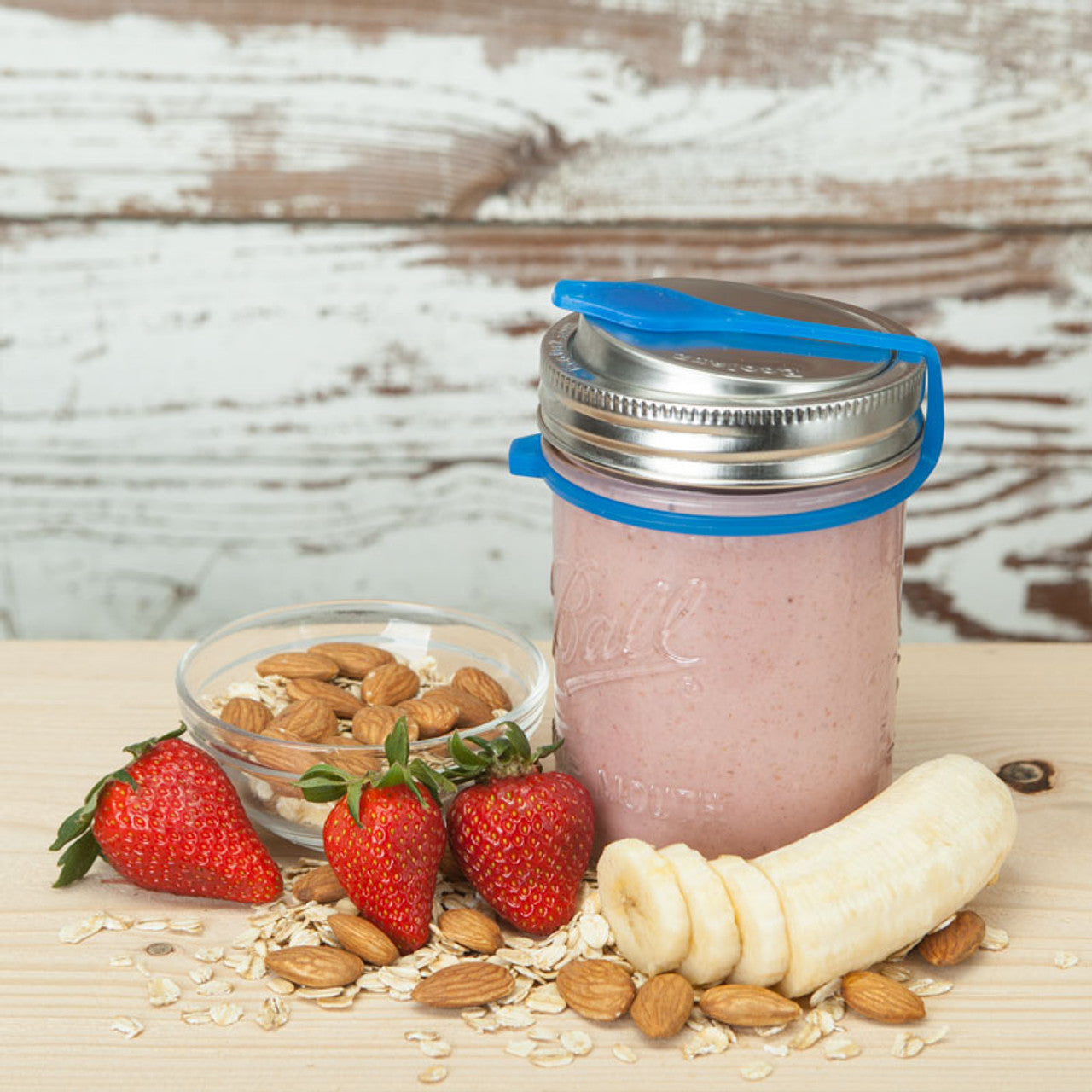 Blue poptop lid with closed plug on a 16 ounce mason jar filled with pink smoothie