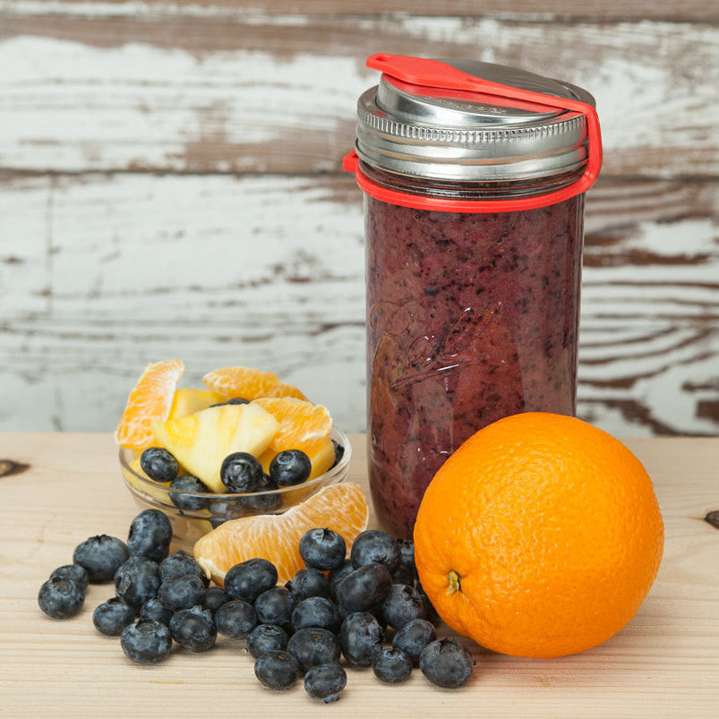 Red Poptop lid with the plug closed to prevent leaking on a 24 ounce mason jar full of a berry smoothie