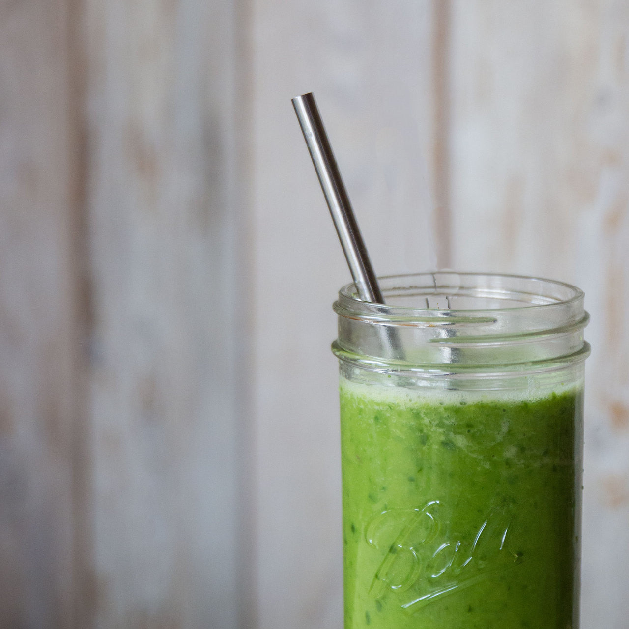 Smoothie straw in a 24 ounce mason jar filled with a green smoothie.