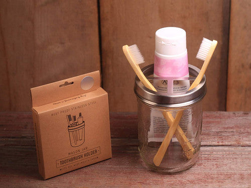 Mason jar with toothbrush holder lid holding two toothbrushes and a tube of toothpaste