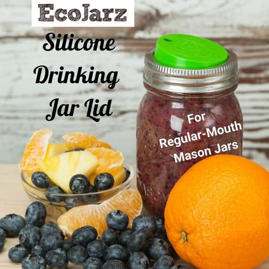 Green Silicone drink lid on a regular mouth mason jar filled with a smoothie and surrounded by fruit.