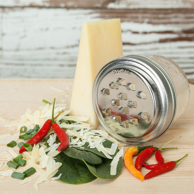 A grater lid attached to a mason jar with grated cheese and a wedge of parmesan cheese