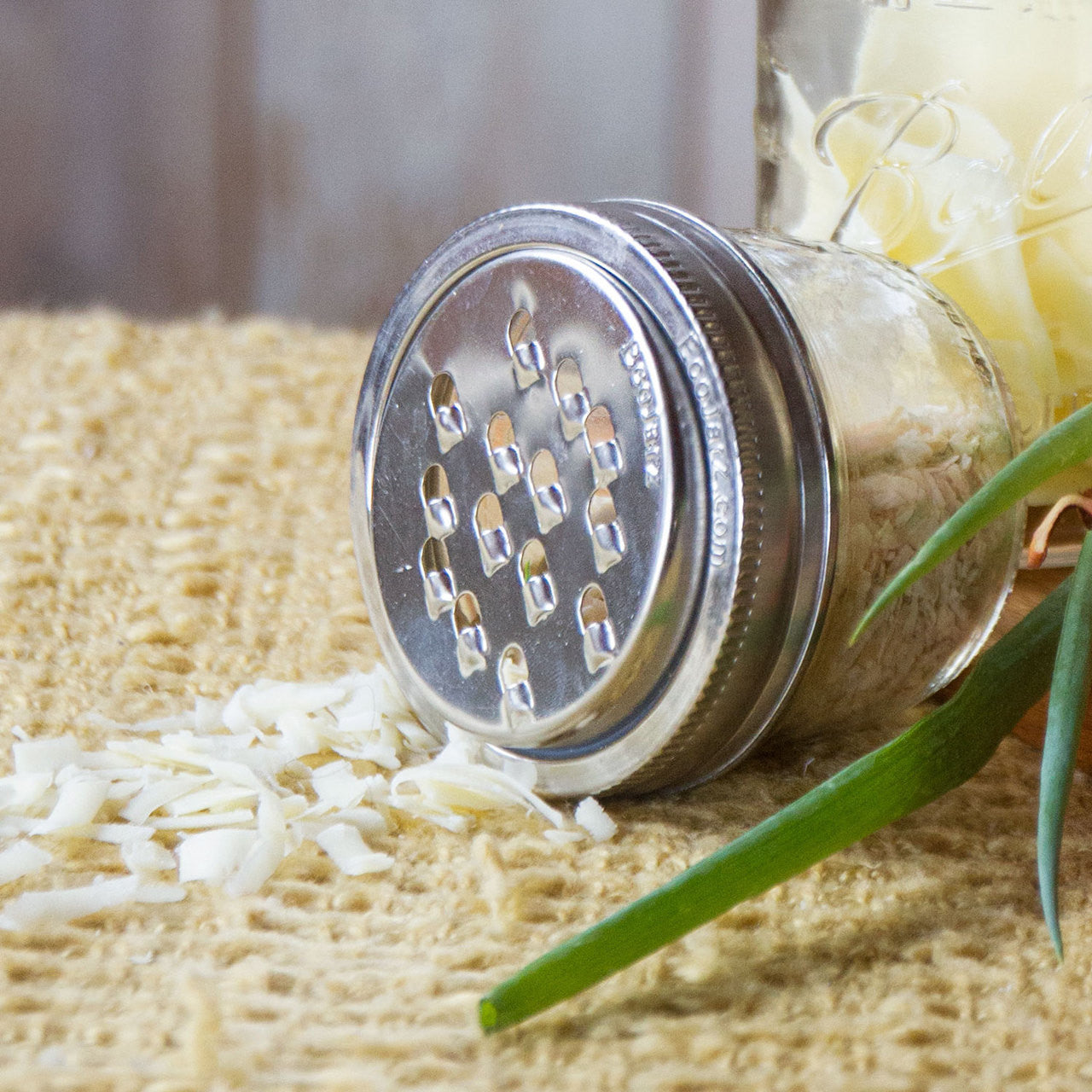 a mason jar with a grater lid and grated cheese around it