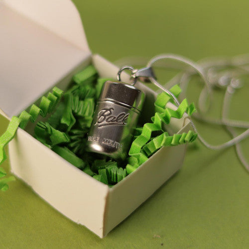 Stainless steel mason jar locket necklace nestled in a small white paper gift box.